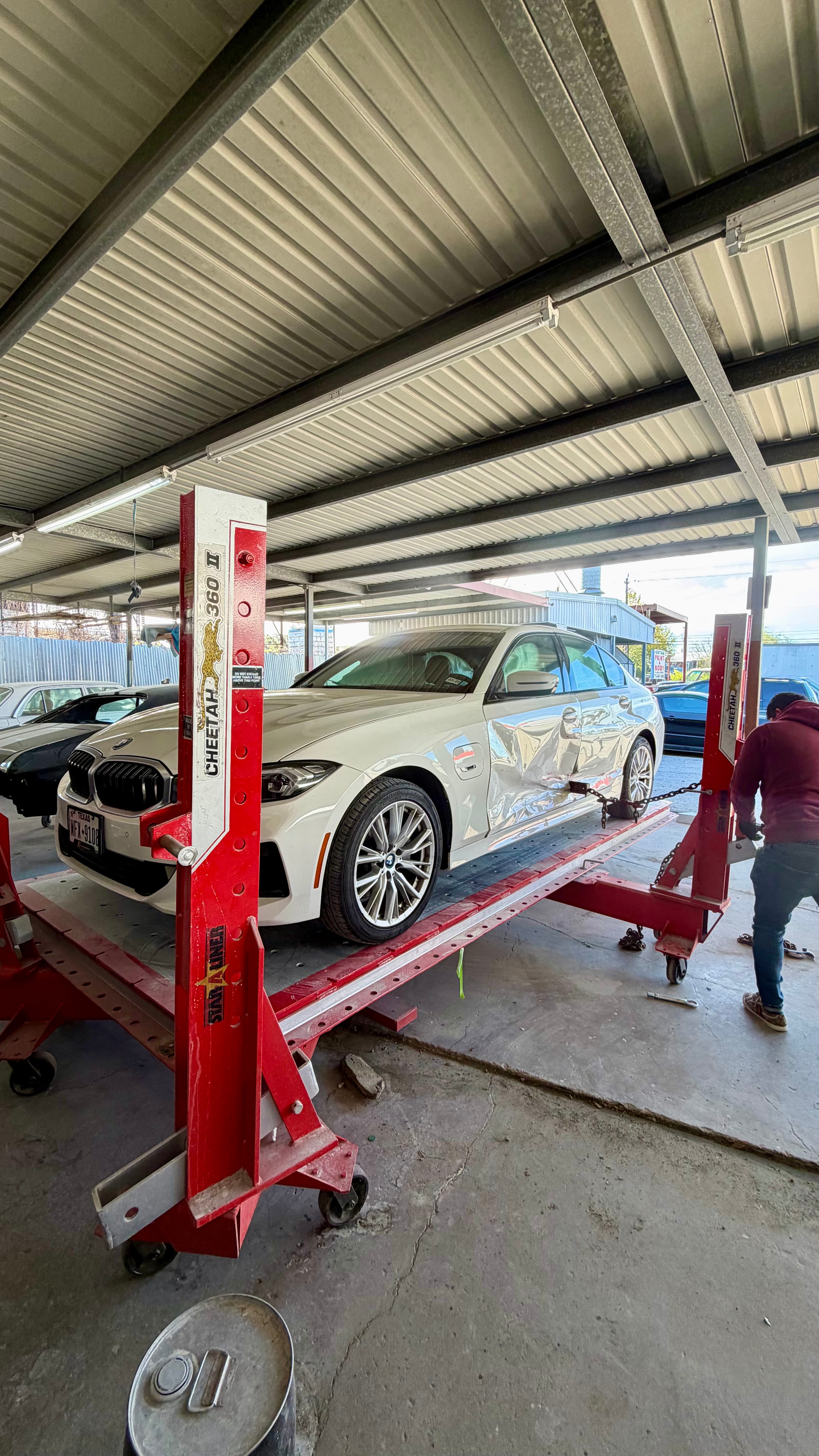 Heritage Paint & Body — BMW on a frame straightening rack during collision repair